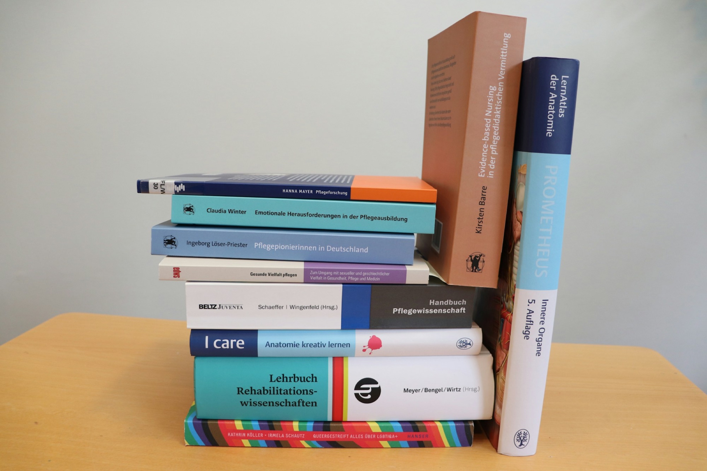 Stack of biomedical research and reference textbooks on a desk.